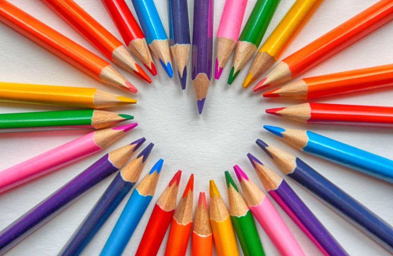 Vibrant colored pencils creatively arranged in a heart shape on a white background.